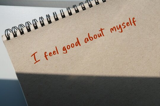 Brown notebook with handwritten text  I FEEL GOOD ABOUT MYSELF - Positive affirmation to boost self confidence - overcome self-doubt and low self-esteem