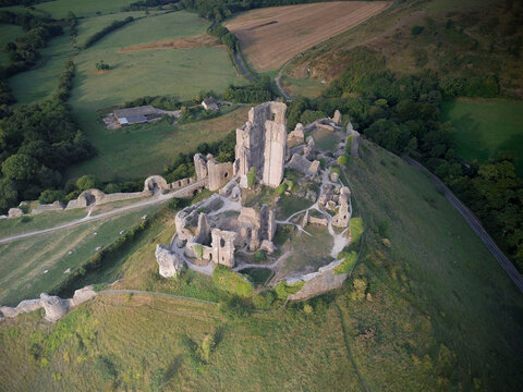 Aerial view of scenic Corfe Castle ruins on a hilltop surrounded by lush countryside, Wareham, United Kingdom.