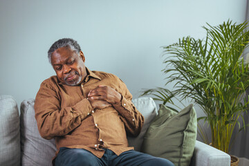 Obraz premium Senior Man Experiencing Chest Pain at Home on Sofa