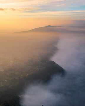 Aerial view of majestic mountains shrouded in mist and clouds at dawn, Tosari, East Java, Indonesia.
