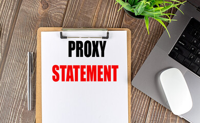 Proxy statement document on a clipboard with a pen, laptop, and plant on a wooden desk