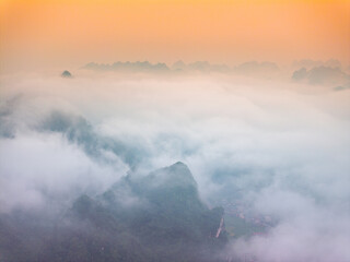 Fototapeta premium Orange sky and sea of clouds before sunrise. A peaceful, refreshing feeling. View of the hills surrounding Ba Quang, Ha Lang district, Cao Bang province, Vietnam