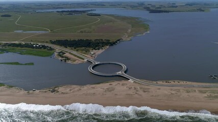 Aerial view of Laguna Garzon Bridge connecting coastal road over tranquil lagoon and ocean, Garzon, Uruguay. - Powered by Adobe