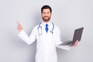 Portrait of experienced doctor man laptop indicate finger empty space wear white coat isolated on grey color background