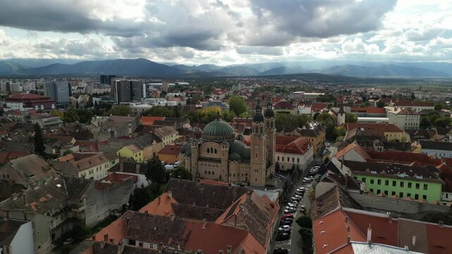Aerial view of a large cathedral with a green dome, surrounded by the city and mountains in the background. Catedrala Ortodoxă "Sf&acirc;nta Treime". Sibiu, Romania.