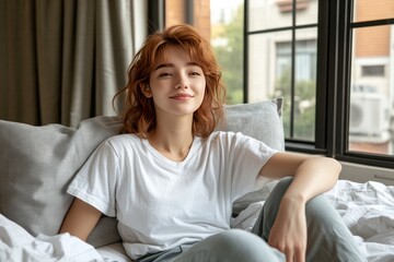 Obraz premium Relaxed woman sitting comfortably by a window in a cozy sunlit space symbolizing a serene and peaceful morning perfect for lifestyle relaxation and wellness concepts