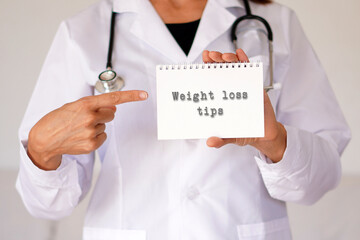 woman doctor pointing with her index finger to a notebook with the words weight loss tips