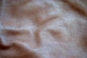 Close-up of brown leather. Brown leather texture. Wrinkled brown leather background with folds.