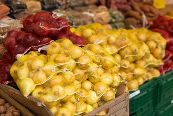 Red and yellow onions in nets at a market stall. Ingredients for cooking and frying. Haagse Market in The Hague, Netherlands.