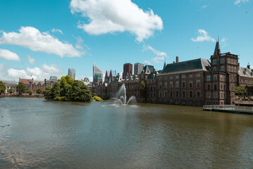 Government and parliament building at Hofvijver lake in The Hague. Fountain in the lake, office buildings and skyscrapers in the background.