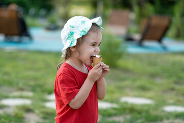 Little girl eating ice cream in the park in summer. Close-up portrait of a child