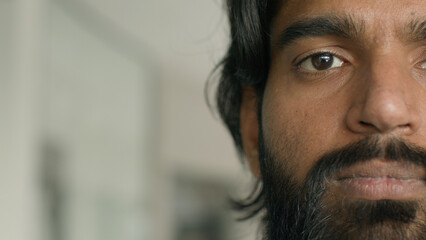 Close-up male portrait half face serious concentrated upset stressed adult bearded indian man frustrated ethnic guy businessman looking at camera details facial part brown eyes vision ophthalmology