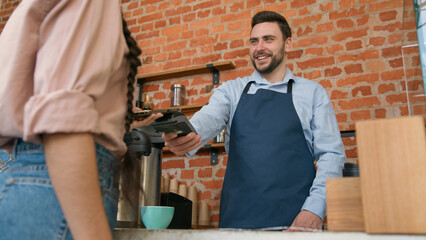 Woman customer pay use contactless payment technology NFC on phone in cafe bar restaurant smiling man waiter barista serving client at counter in cafeteria girl paying through bank mobile app terminal