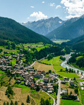 Aerial view of a picturesque village nestled in a tranquil valley surrounded by majestic mountains and lush forests, Cogne, Italy.