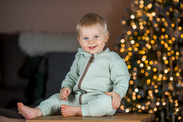 Family and children. A beautiful blond boy of 1 year old on the background of a Christmas tree. The...