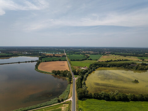 Aerial view of serene Parc des Oiseaux with lush fields, tranquil lake, and vibrant greenery, Marlieux, France.