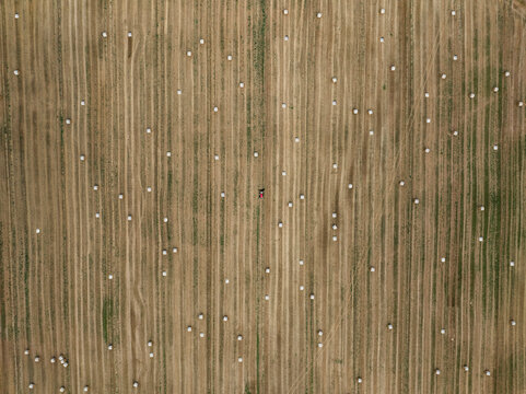 Aerial view of a beautiful countryside with a haystack field and tractor, Varennes-Saint-Sauveur, France.