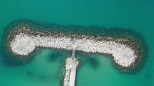 Aerial view of the beautiful Port des Sablettes with a tranquil coastline and rocky structures, Menton, France.
