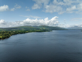 Aerial view of tranquil Loch Lomond surrounded by majestic mountains and serene clouds, Trossachs National Park, Scotland.