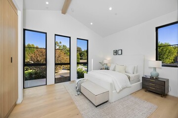 Modern bedroom with large windows and cozy decor.