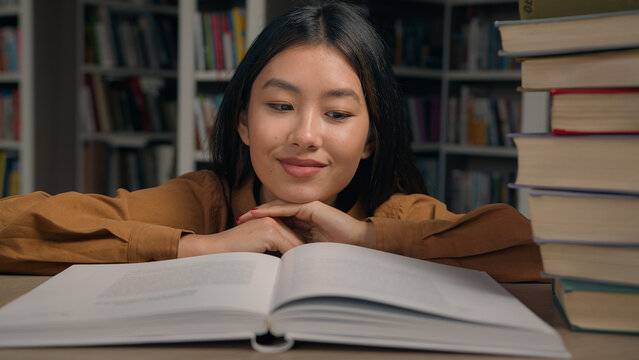Close-up asian woman student read book in university library smiling girl lady reader enjoy reading novel literature looking at textbook studying information preparing for college exam doing homework