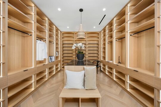 Modern walk-in closet with wooden shelves and elegant lighting.