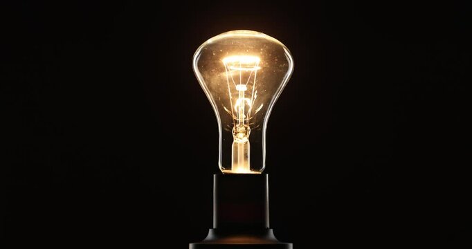A bright, smooth ignition and dimming of an incandescent electric bulb against a black background