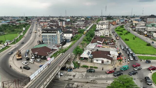 Aerial view of busy npogu junction with moving cars and a train, Port Harcourt, Nigeria.