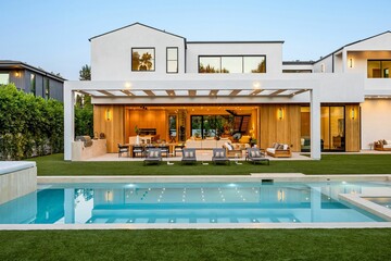 Modern luxury home with pool at dusk.