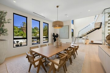 Modern dining room with wooden table and large windows.