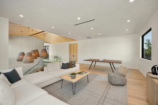 Modern living room with sectional sofa and ping pong table. - Powered by Adobe