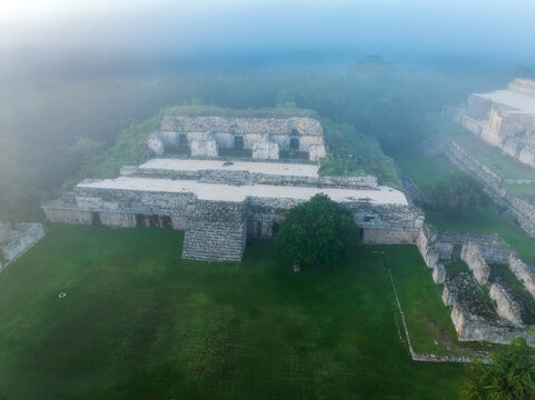 Aerial view of ancient stone ruins surrounded by lush greenery and mist, Santa Elena, Yucatan, Mexico.