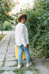 Fototapeta premium The woman smiles and pulls a yellow suitcase behind her
