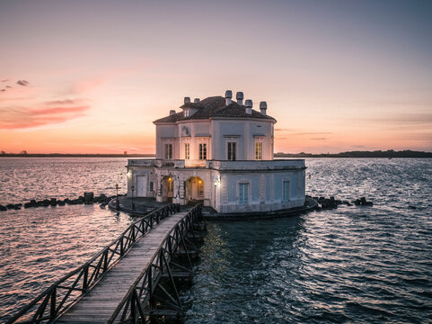 Aerial view of fusaro lake with the elegant casina vanvitelliana at sunset, bacoli, italy.