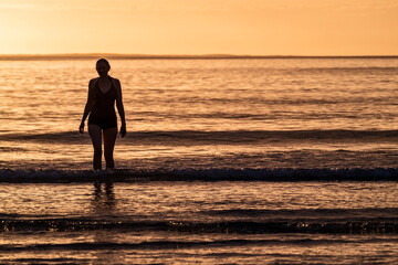 Silhouette of female swimmer going into the Atlantic ocean in Ireland