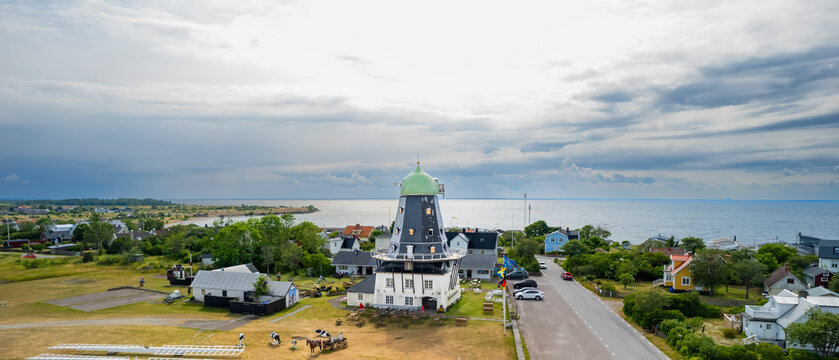 Aerial view of a picturesque traditional mill and charming homes along the tranquil coast, Oland Island, Sweden.