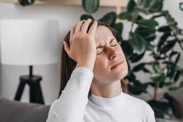 Close up of dizzy young female headache or migraine pain suffering from vertigo or sick, holding...