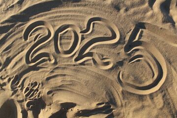 Obraz premium 2025 is written on the sand on the ocean. New Year's Eve celebration by the sea