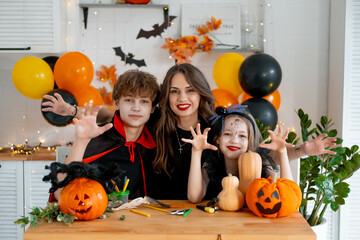 Happy family preparing for Halloween. Mother and children in carnival costumes at home in the...