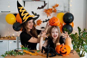 A happy family is getting ready for Halloween. Mother and child daughter in carnival costumes at...