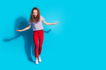 Joyful woman in colorful casual outfit posing with excitement against a vibrant blue background.