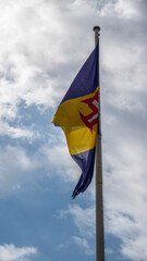 The flag of Madeira fluttering against a partly cloudy sky, symbolizing the vibrant culture and heritage of this Portuguese island