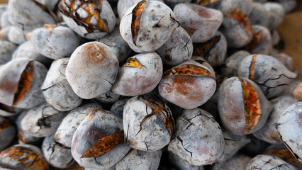 Close-up of roasted chestnuts with cracked shells, revealing their golden interiors, commonly enjoyed as a warm seasonal treat