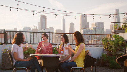 Group Of Female Friends Celebrating Birthday On Rooftop Terrace With City Skyline In Background