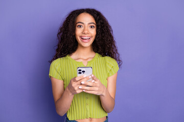 Photo portrait of pretty teen girl hold gadget excited wear trendy green outfit isolated on purple...