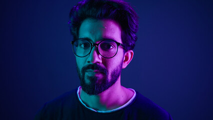 Close up portrait neon ultraviolet background Indian man guy developer coder smart hacker clever...