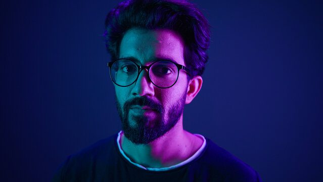 Close up portrait neon ultraviolet background Indian man guy developer coder smart hacker clever coding computer engineer showing gesture think about it thinking hard brain mental ponder IQ remember