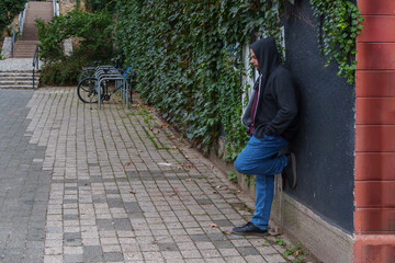 Man leaning against a wall on a quiet street