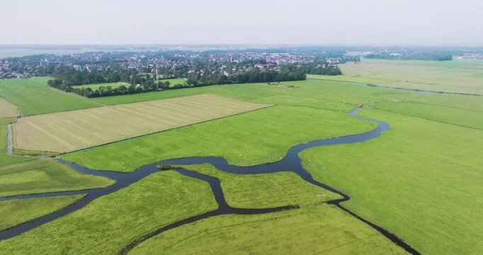Aerial view of meadow bird reserve Oosterveld with tranquil water in front of the peaceful village Limmen, Noord-Holland, Netherlands.