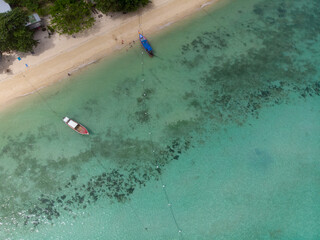 Aerial view of boats anchored by a tropical beach.
